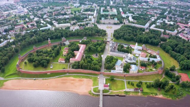 Panoramic aerial view of the Volkhov River and the old town of Veliky Novgorod, the red brick Kremlin in the rays of the setting sun and natural attractions of Russia.