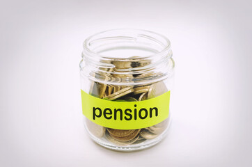 Coins in a glass money jar with retirement label, financial concept.
