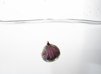 Fresh figs falling deeply into clear water isolated on a white background. Healthy food diet...