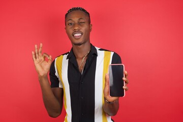 Portrait African american man with braids wearing casual shirt over isolated red background holding...