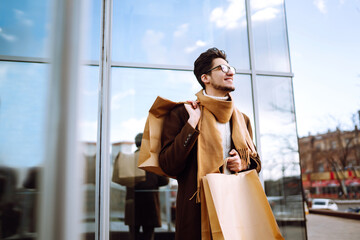 Stylish man with paper packages after shopping. Young man with shopping bags walking around the...