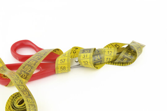 Tijera envuelta por un metro, donde se cortan los cenímetros de más. Esta imagen es ideal para aquellos proyectos que hablen sobre dietas, bajar de peso y temas relacionados. 