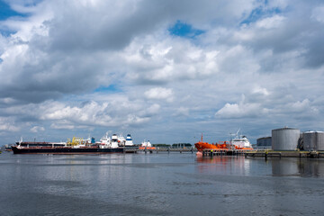 Naklejka premium Tanker and oil storage tanks in Rotterdam, Netherlands. The port is the largest in Europe and facilitate the needs of a hinterland