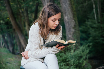 Young woman reading a book outdoors