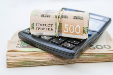 Money stack / 500 hryvnia rolled into a roll and calculator / Financial concept.