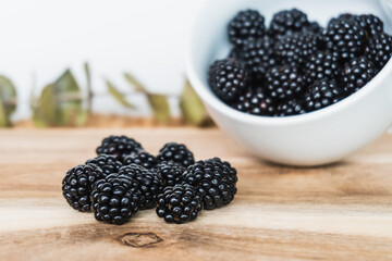 Close-up of a bowl full of wild blackberries on rustic wood.