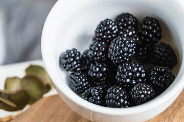 Close-up of a bowl full of wild blackberries on rustic wood.