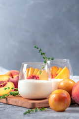 Yoghurt with fresh peaches on light background