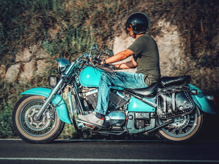 Obraz na płótnie Canvas Biker riding a classic motorcycle on a country road
