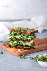 Sandwich with cucumber, cheese and herbs on light background
