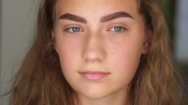 Professional styling, correction and lamination procedures of female eyebrows in beauty salon. Closeup view of young female client face after procedure.