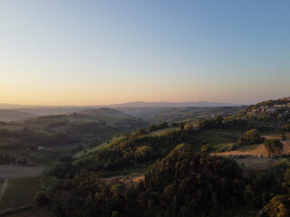 Tuscany, rural landscape in Crete Senesi land. Rolling hills, countryside farm, cypresses trees, green field on warm sunset. Siena, Italy