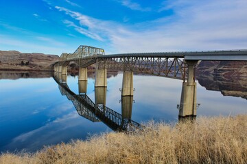 Reflection of bridge on calm river 