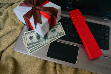 Gift in a white package on a black laptop keyboard and dollars. purchase.