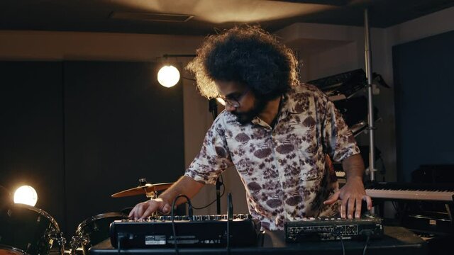 Music concept. Beatmaking. Hispanic man recording new beats. An intelligent brunette male person with afro hair records his ideas.