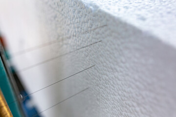 Industrial production of polystyrene foam insulation panels or plates. A large blocks of Styrofoam is cut into plates with hot strings in a automated machine. Production of a building materials.