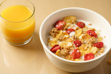 Bowl of Breakfast Cereal with strawberries, almonds, granola and a glass of orange juice 