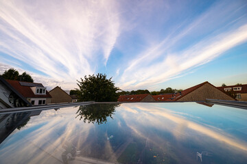 Cirrus clouds that appear to come from one point are reflected in the glass of a roof window