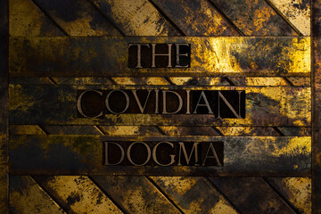 The Covidian Dogma text formed with real authentic typeset letters on vintage textured silver grunge copper and gold background