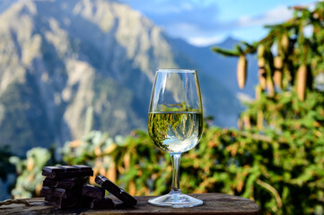 Glass of swiss or savoy dry white wine, pure chocolate with Alpine mountains peaks on background