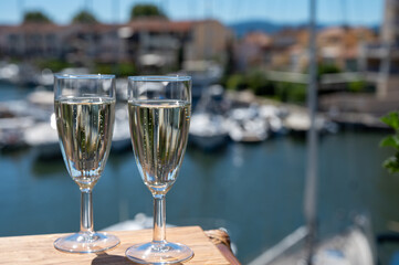Summer party with sparkling champagne wine and sail boats haven of Port Grimaud on background, Provence, France