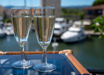 Summer party with sparkling champagne wine and sail boats haven of Port Grimaud on background, Provence, France