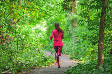 Run in forest at fall. Fit woman running in nature outdoors doing fitness workout in autumn park. Girl athlete jogging outdoor. © Maridav