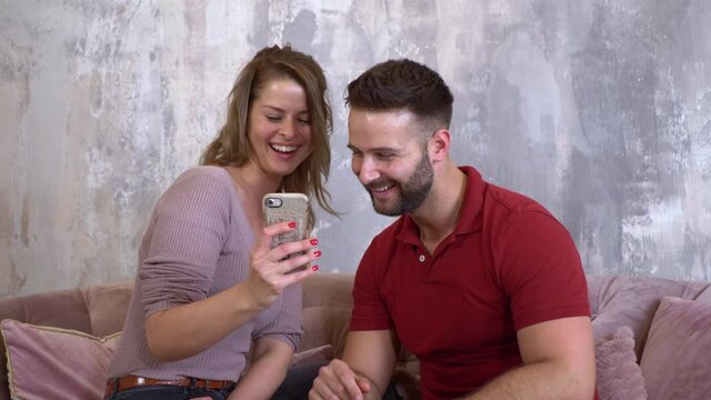 Couple Looking At family Photos On Phone, Laughing And Smiling