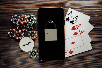 Smartphone with padlock, poker chips and playing cards. Concept of Law and regulation of gambling.