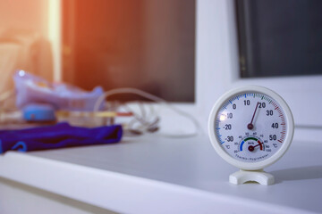 On the windowsill a round thermometer hygrometer indicates eighteen percent humidity