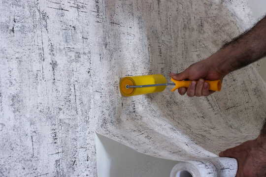 The Builder glues the Wallpaper and levels it with a roller. Close-up