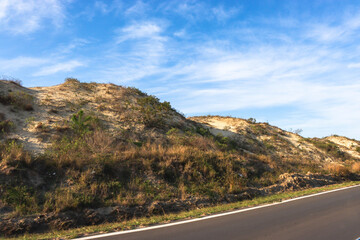 
sand hill with grass on the side of the road