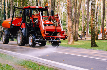 cleaning the park, a small tractor watering the sidewalk