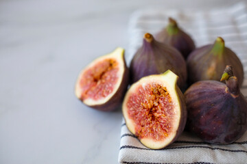 Whole figs and one fig sliced in half on top of a teak garden table. Focus is on the sliced fig....