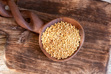 Fenugreek seeds on a wooden spoon on a table