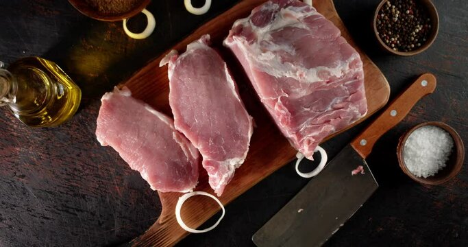 Raw pork escalope slowly rotates on a cutting board. 