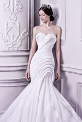 Elegant woman princess wearing a beautiful high fashion haute couture wedding dress against baroque...