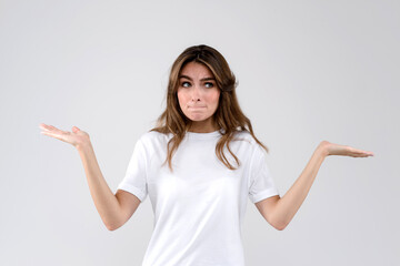 Woman standing on a white background throwing up her hands in doubt. Human emotions