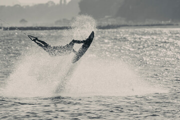 Fototapeta premium WAKEBOARDING AT THE SEA JUMPING HIGH DOING A BACKFLIP IN BLACK AND WHITE