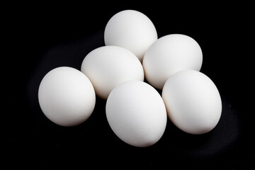 half dozen white eggs lying loose on a black background
