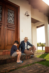 Garoto joga de xadrez com seu avô na escada de casa.