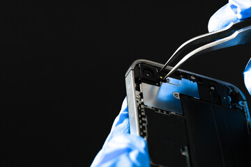 Technician repairing mobile phone at table, parts and tools for recovery repair smartphone's...