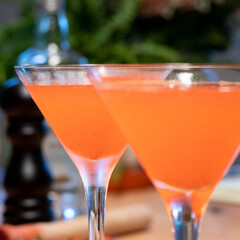 Two Strawberry Cocktail in martini glass with strawberry in garnish side view with plant background
