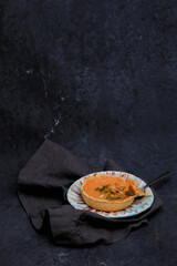 traditional halloween pumpkin seed autumn pie on ceramic plate with spoon on black towel on dark vintage background