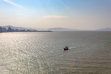 Florianopolis e Barco navegando no mar com a vista da Beira Mar Continental, Florianópolis, Santa Catarina, Brasil