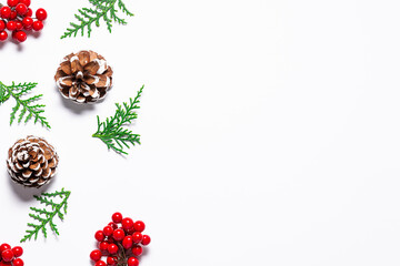 Minimalism style Christmas composition with fir tree twigs, pine cones and bright red berries on white background top view. 