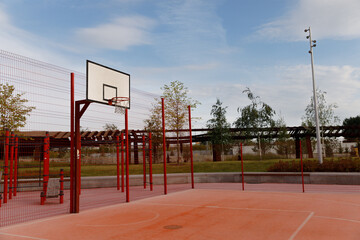 Basketball playground without people, outdoor sports ground, park, trees, sky.