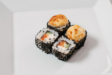 Top view of assorted sushi rolls on white plate.