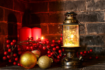 Vintage christmas lantern with golden balls, red berries, red candles on fireplace, happy new year