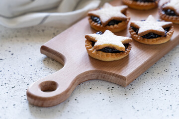 Christmas homemade mince pies on wooden paddle board on white background
